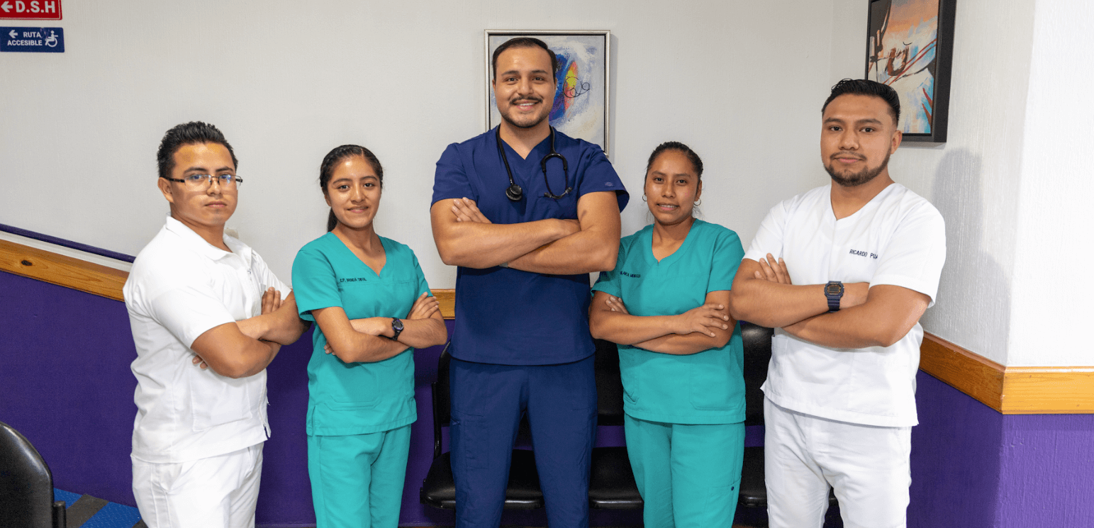 Pediatra del centro médico MediFam atendiendo a un niño en brazos de su madre indígena, en una consulta colorida y amigable en Sololá.